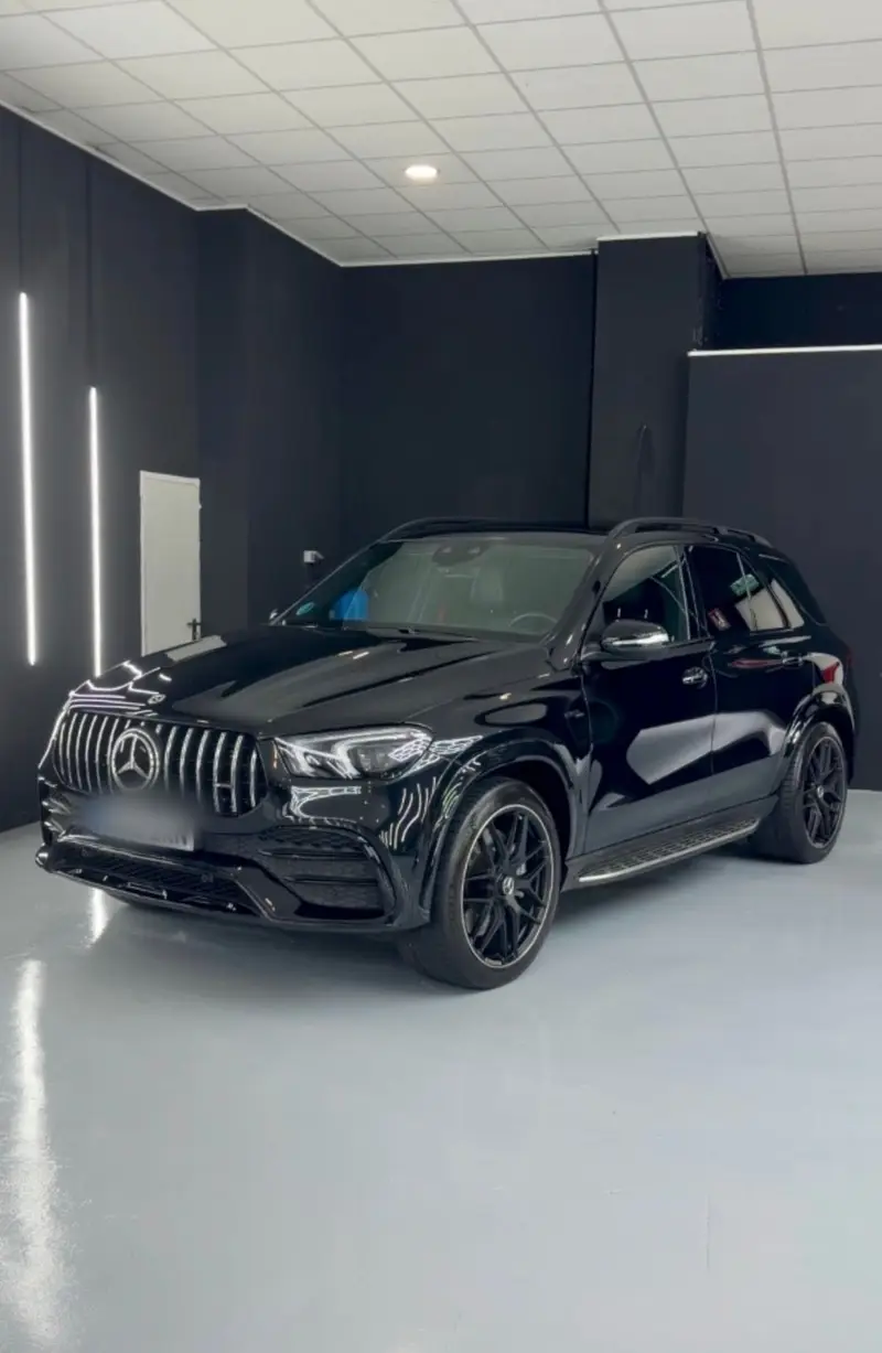 Mercedes-AMG GLE negro en la sala de la nave, con las tiras LED reflejadas en la chapa