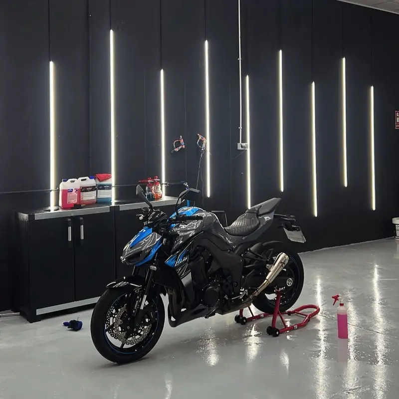 Kawasaki Z negra y azul sobre el caballete, frente a la pared de tiras LED
