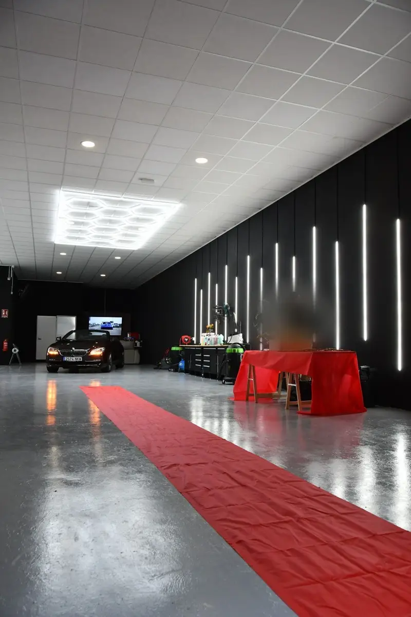 Interior de la nave de Brilla: paredes negras con tiras LED verticales y una alfombra roja sobre el suelo claro